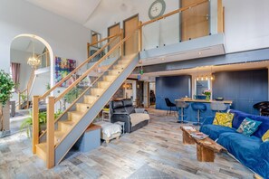 A spacious living area with a staircase, a blue sofa, and a kitchen area. - 3 Bed in Crowle (oc-s30617) (Crowle)