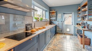 A modern kitchen with a long countertop, built-in oven, and a window overlooking a garden. - 3 Bed in Crowle (oc-s30617) (Crowle)