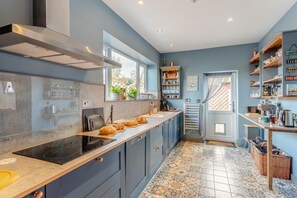 Eine moderne Küche mit langer Arbeitsplatte, eingebautem Backofen und Fenster mit Blick auf einen Garten.
