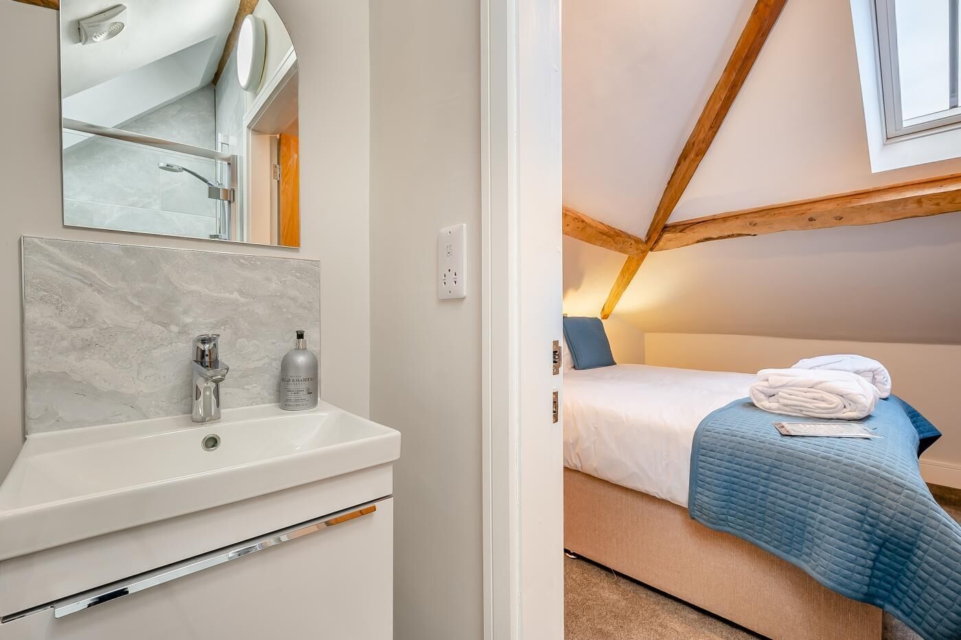 A bedroom with a bed, a blue blanket, and a white towel.