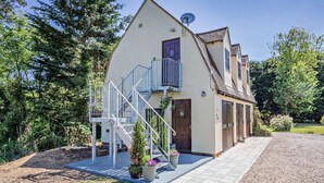 Une maison à deux étages avec un balcon, une antenne parabolique et une allée.