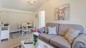 Un salon comprenant un canapé, une table à manger, des chaises, un lustre et un tableau accroché au mur.