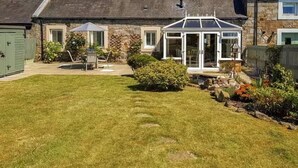 Une maison avec une véranda, une pelouse et un abri de jardin.