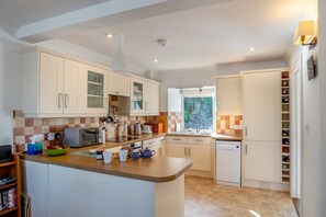Cocina moderna con armarios blancos, una isla central, horno empotrado y ventana que aporta luz natural.
