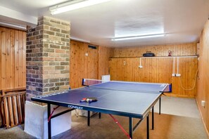 Ein Tischtennistisch in einem Raum mit Holzwänden und einer Ziegelstütze.