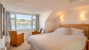 Een slaapkamer met een groot bed, een bureau en uitzicht op zee.