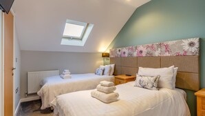 A bedroom with two beds, a skylight, a radiator, and a floral headboard. - 6 Bed in Winnards Perch (oc-c30624) (Winnard's Perch)