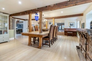 A spacious dining area with a wooden table and chairs, a chandelier, and a stone fireplace. - 6 Bed in Llanfilo (oc-e30630) (Llanfilo)