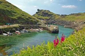 A harbor with boats docked, a stone pier, and a grassy hill in the background. - 3 Bed in Delabole (oc-t30590) (Delabole)