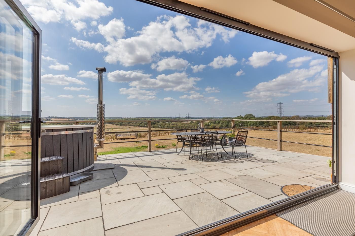 Un balcon avec une table et des chaises, un jacuzzi et une vue sur la campagne.