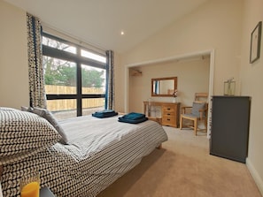 A bedroom with a large bed, a wooden dresser, a mirror, and a desk.