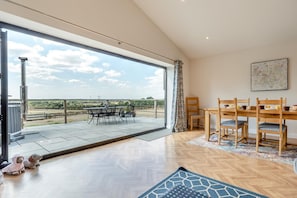 A spacious room with a large sliding glass door leading to an outdoor patio with a table and chairs.