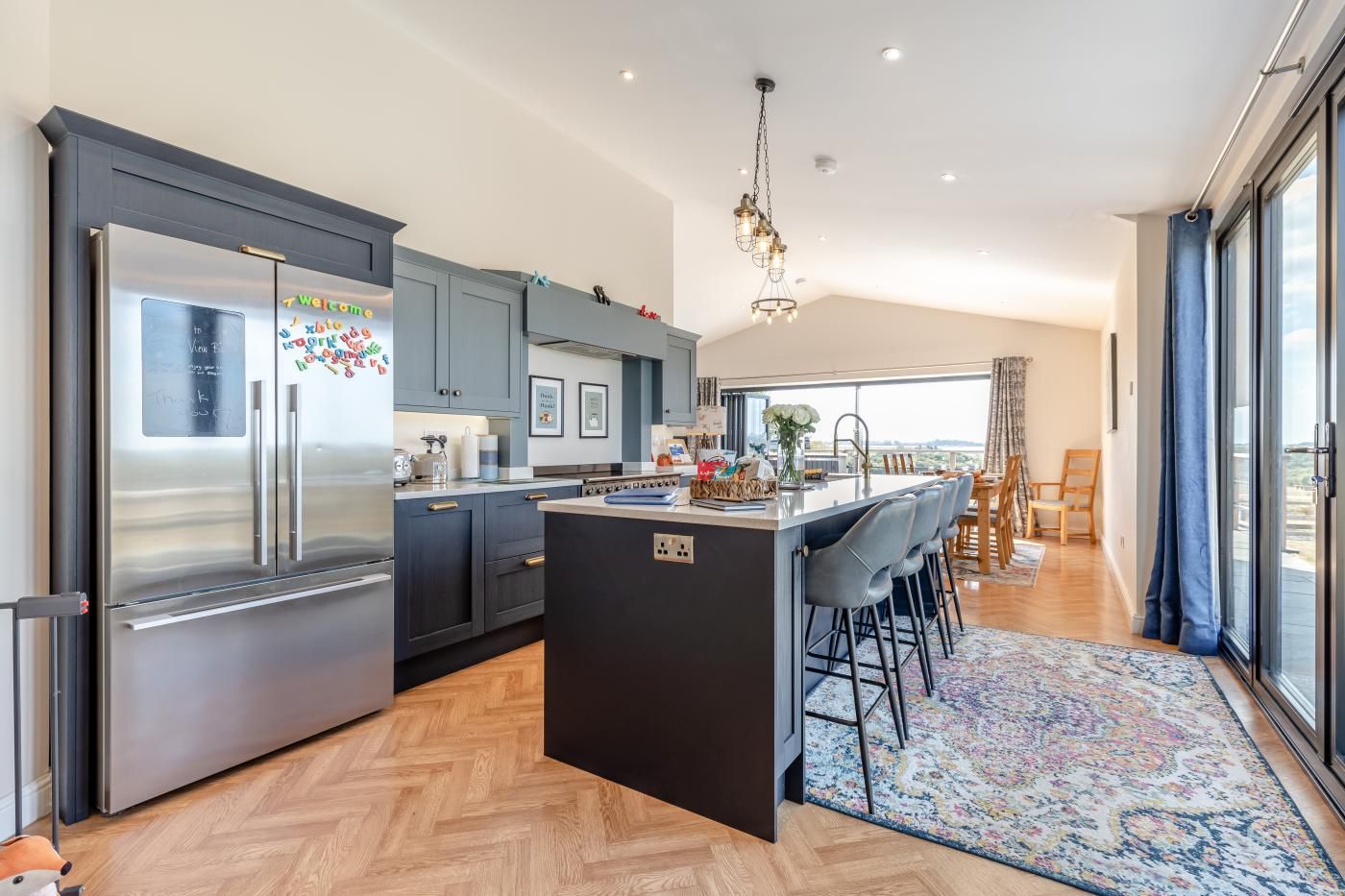 A modern kitchen with a central island, stainless steel appliances, and a view to the outside.
