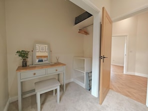 A bedroom with a bed, a bedside table, a mirror, and a wardrobe.