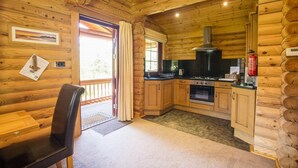 A log cabin with a kitchen featuring wooden cabinets, a stove, and a fire extinguisher. - 2 Bed in Felton (oc-c30643) (Thirston)