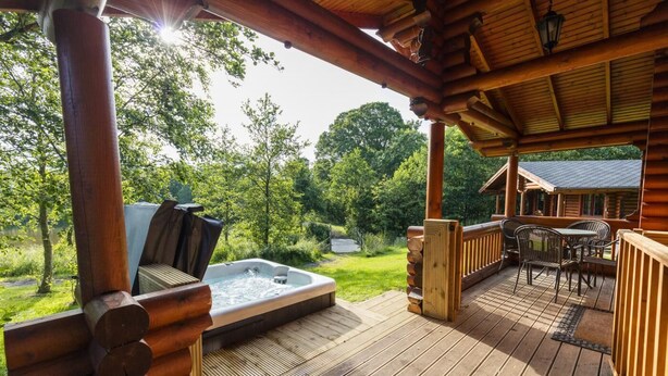 A wooden deck with a hot tub, outdoor furniture, and a view of a lake and trees. - 2 Bed in Felton (oc-c30643) (Thirston)