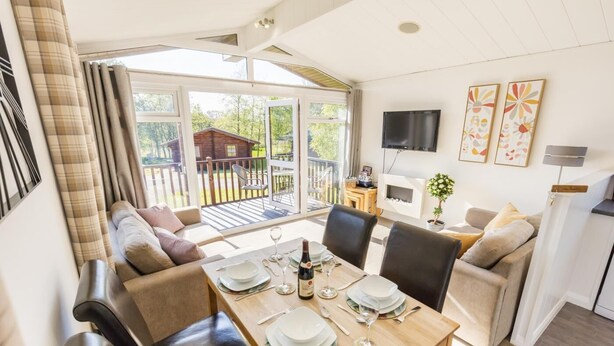 Una sala de estar moderna con comedor, ventanas grandes y vistas al exterior.