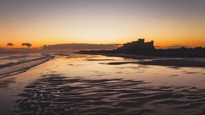 A beach with a castle silhouette during sunset. - 2 Bed in Swarland (oc-c30636) (Swarland)