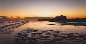A beach with a castle silhouette during sunset.