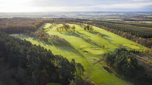 An aerial view of a golf course with multiple holes, surrounded by dense forests and open fields. - 2 Bed in Swarland (oc-c30636) (Swarland)