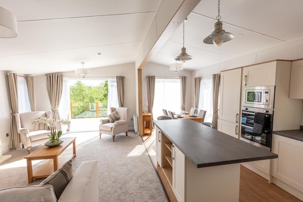 A modern kitchen with a central island, a dining area with a table and chairs, and a living room with a sofa and a coffee table.