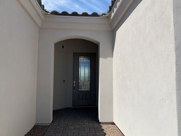 A narrow hallway leading to a dark door with a glass panel. - Gorgeous Pool and RV Garage Home! (Lake Havasu City)