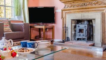 Un salon comprenant un téléviseur, une cheminée et un coin repas avec des assiettes et un gâteau.