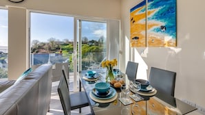 A dining area with a table set for two, a sofa, and a view of the outdoors.