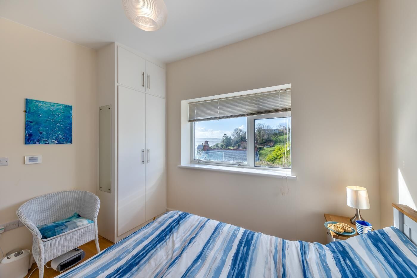 Une chambre à coucher comprenant un lit, une chaise, une armoire, une fenêtre donnant sur un beau paysage et une lampe.