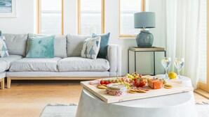 Un salon avec un canapé, une table basse sur laquelle sont disposés des aliments et des boissons, et une lampe.