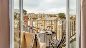 A balcony with a view of terraced houses, a table with a newspaper, and a chair. - 3 Bed in St. Ives (oc-s30653) (Saint Ive)
