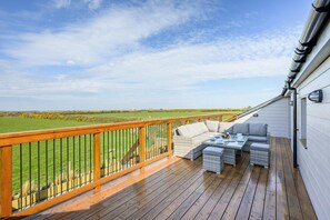 A wooden deck with outdoor furniture, a railing, and a view of a green field. - 3 Bed in St. Mawgan (oc-h30677) (Saint Eval)