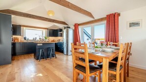 Una cucina moderna con mobili scuri, un frigorifero in acciaio inox e un tavolo da pranzo in legno apparecchiato per quattro persone.