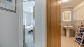 Une salle de bain moderne avec un lavabo sur colonne, un miroir et une étagère contenant des articles de toilette.