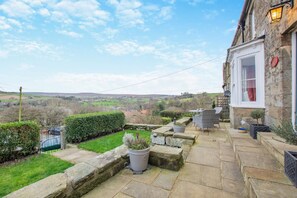 Ein Steinhaus mit Terrasse, Blick auf die Landschaft und einem kleinen Garten.