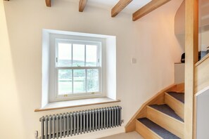 Ein Zimmer mit Fenster, Heizkörper und einer Holztreppe.