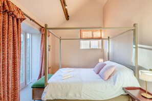 A four-poster bed with a green bench, a bedside table with a lamp, and a window with curtains. - 2 Bed in Llangedwyn (oc-l30530) (Llangedwyn)