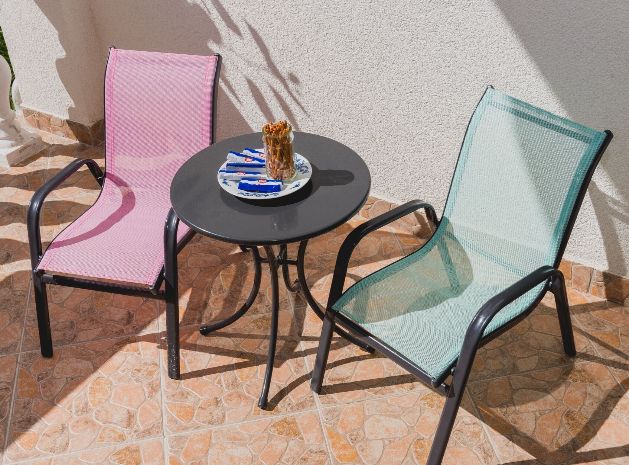 Deux chaises avec un dossier en tissu grillagé et une table sur laquelle se trouve une assiette de collations.