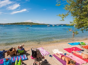 A beach with clear blue water, people sunbathing, and boats in the distance. - Apartments Gabi - Two Bedroom/Balcony/SeaView (A3) (Srima)