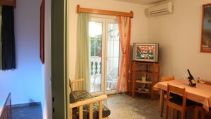 A dining area with a television, a table set for two, and a window with curtains. - Apartments Gabi - Two Bedroom/Balcony/SeaView (A3) (Srima)