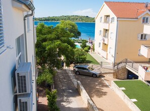 Ein Küstengebäude mit Pool, einem Parkplatz davor und Blick auf das Meer.