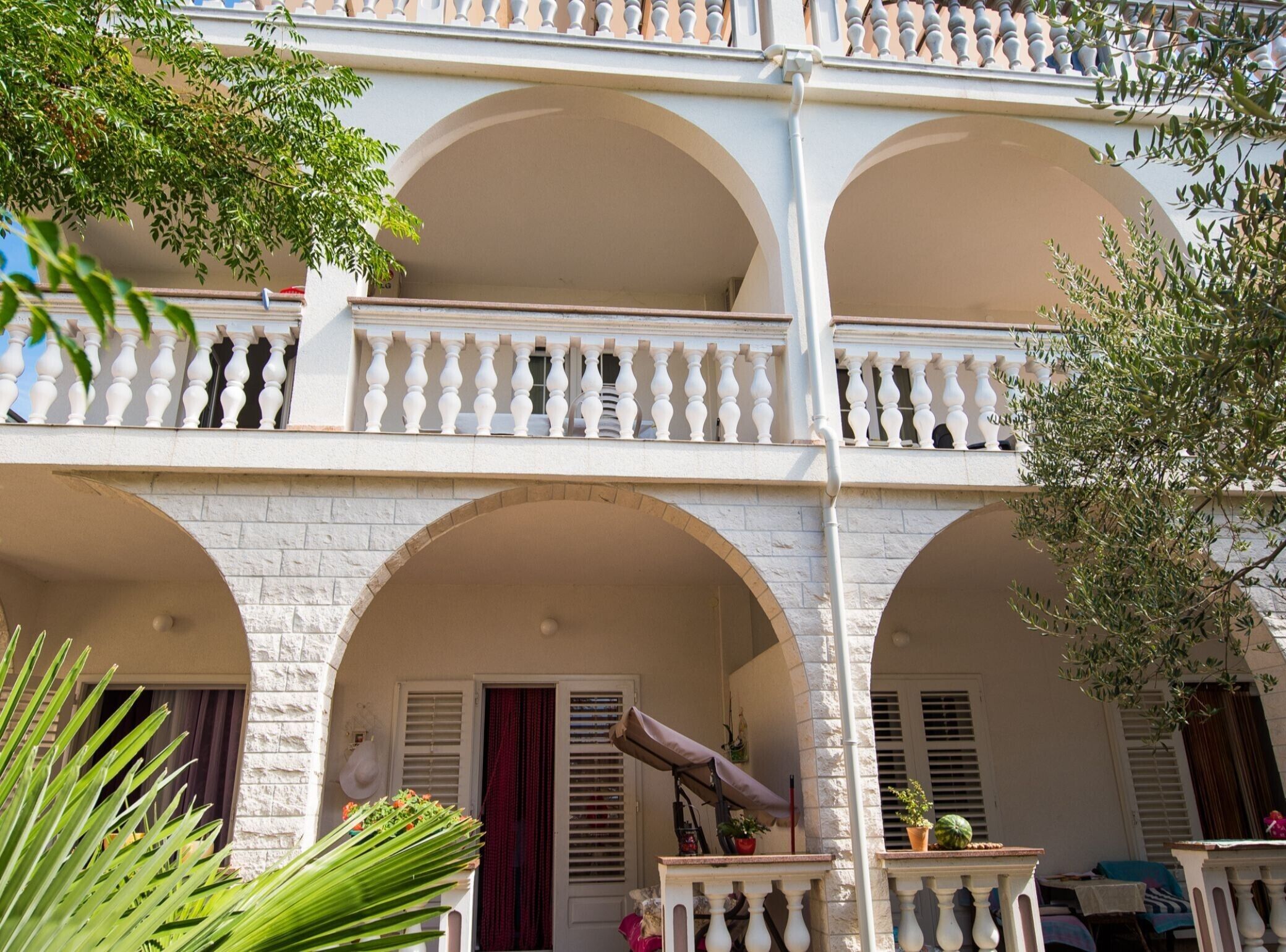 A multi-story building with a white facade, arched balconies, and a covered entrance.