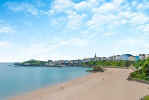 Un pueblo costero con una playa arenosa, un muelle y edificios coloridos a lo largo de la costa.