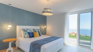 Una camera da letto con un letto, un comodino, una lampada a sospensione e vista sull'esterno.