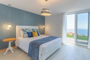 Ein Schlafzimmer mit Bett, Nachttisch, Hängelampe und Blick ins Freie.