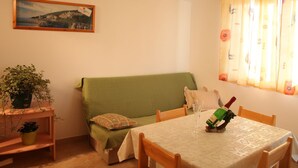 A cozy living room with a green sofa, a small table with a bottle of wine, and a framed picture on the wall. - Apartments Gabi - One Bedroom with Sea View (B1) (Srima)