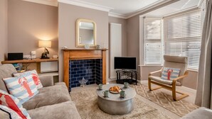 A living room with a fireplace, a television, a sofa, and a chair. - 2 Bed in Sheringham (oc-h30635) (Sheringham)