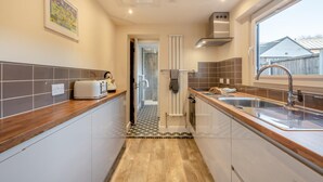 A narrow kitchen with a toaster, a kettle, and a sink. - 2 Bed in Sheringham (oc-h30635) (Sheringham)