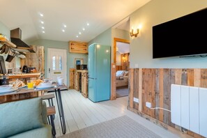 Una cucina moderna con elementi in legno, un frigorifero blu e una TV a schermo piatto montata a parete.