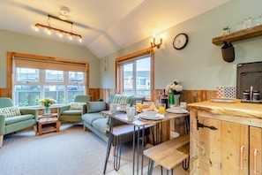 A cozy room with a sofa, chairs, a dining table with breakfast, and a kitchen area. - 2 Bed in Eccles-on-Sea (oc-s30665) (Eccles-on-Sea)